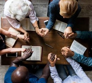 Group of people holding hands praying