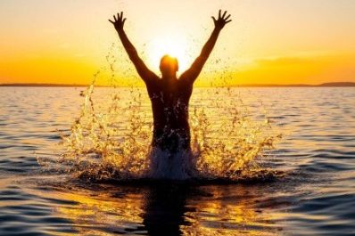 Silhouette of man celebrating in water.