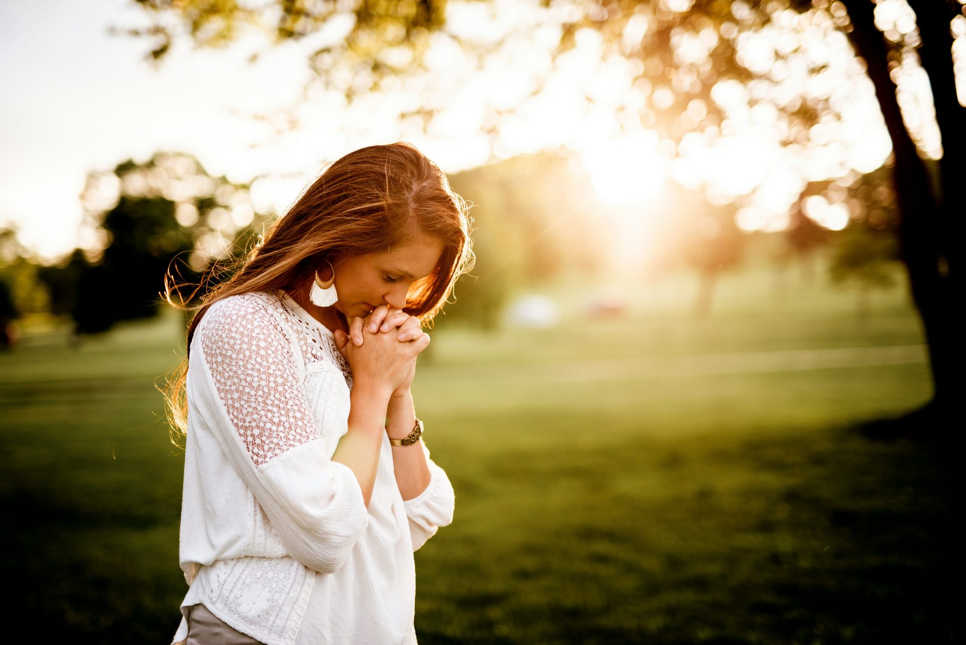 Woman praying outside in serene sunlight